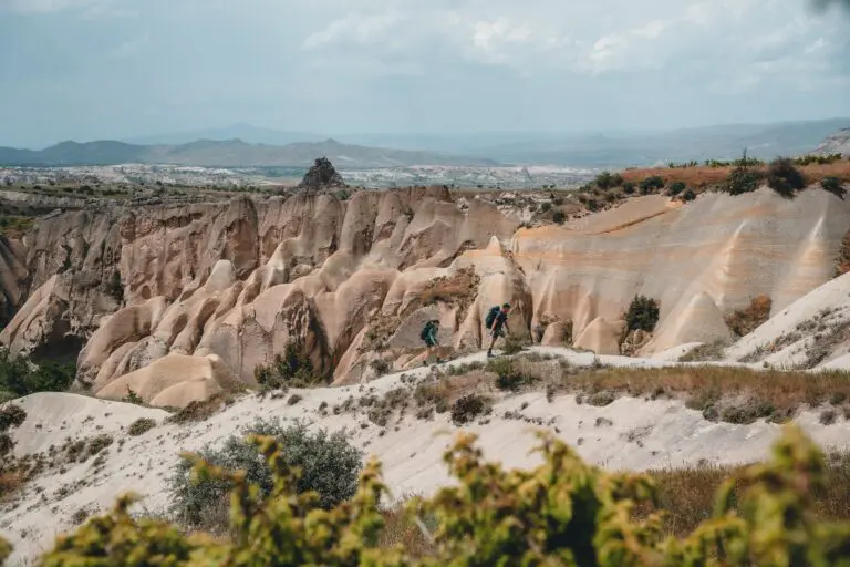two hikers with backpacks in a vast rocky landscape